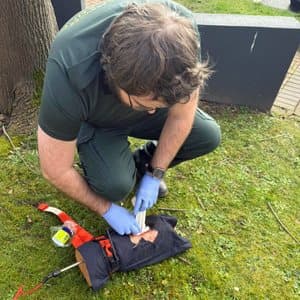 Learner treating a simulated leg wound outdoors