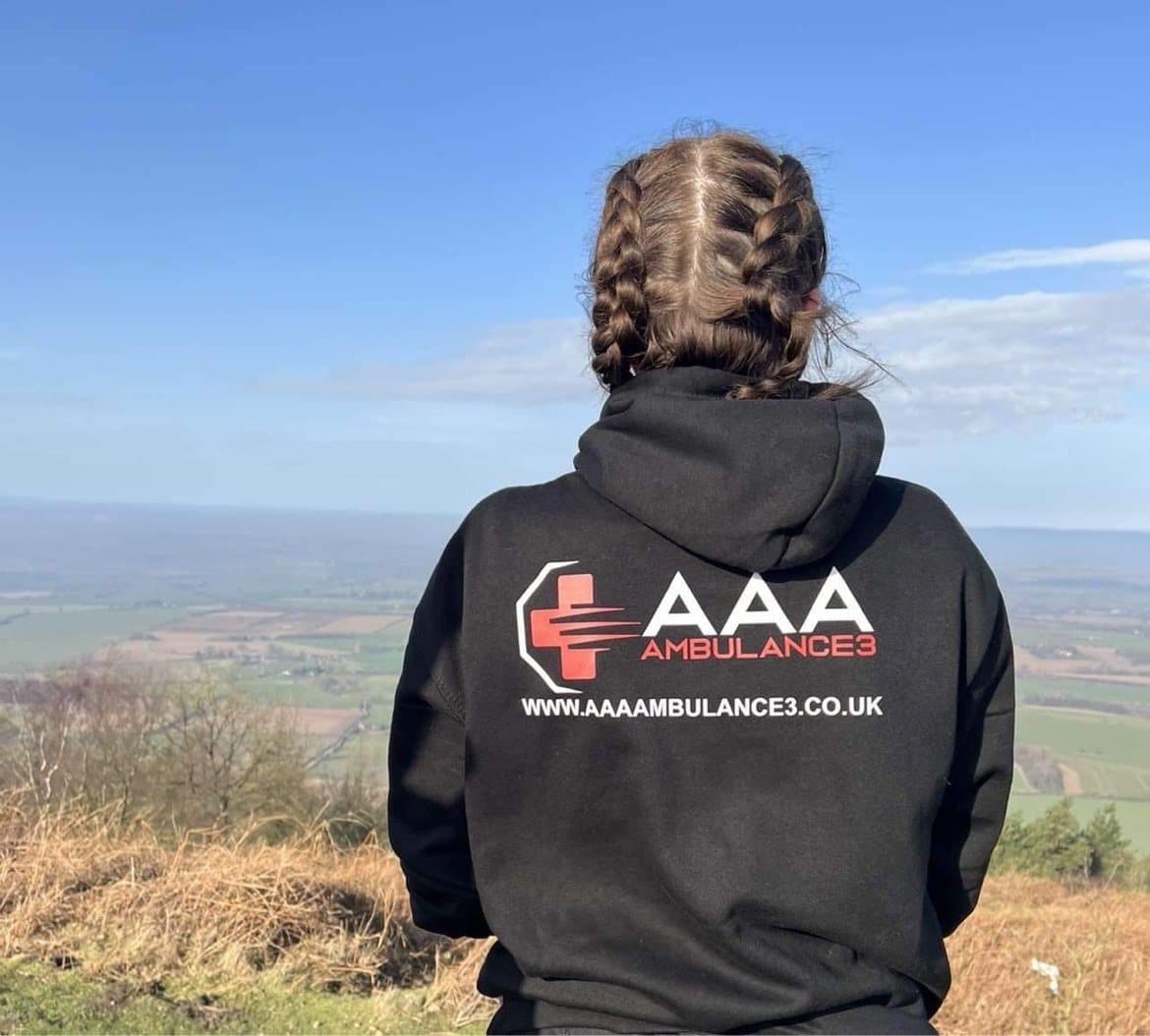 AAA.AMBULANCE3 team member in a branded hoodie looking out over the countryside