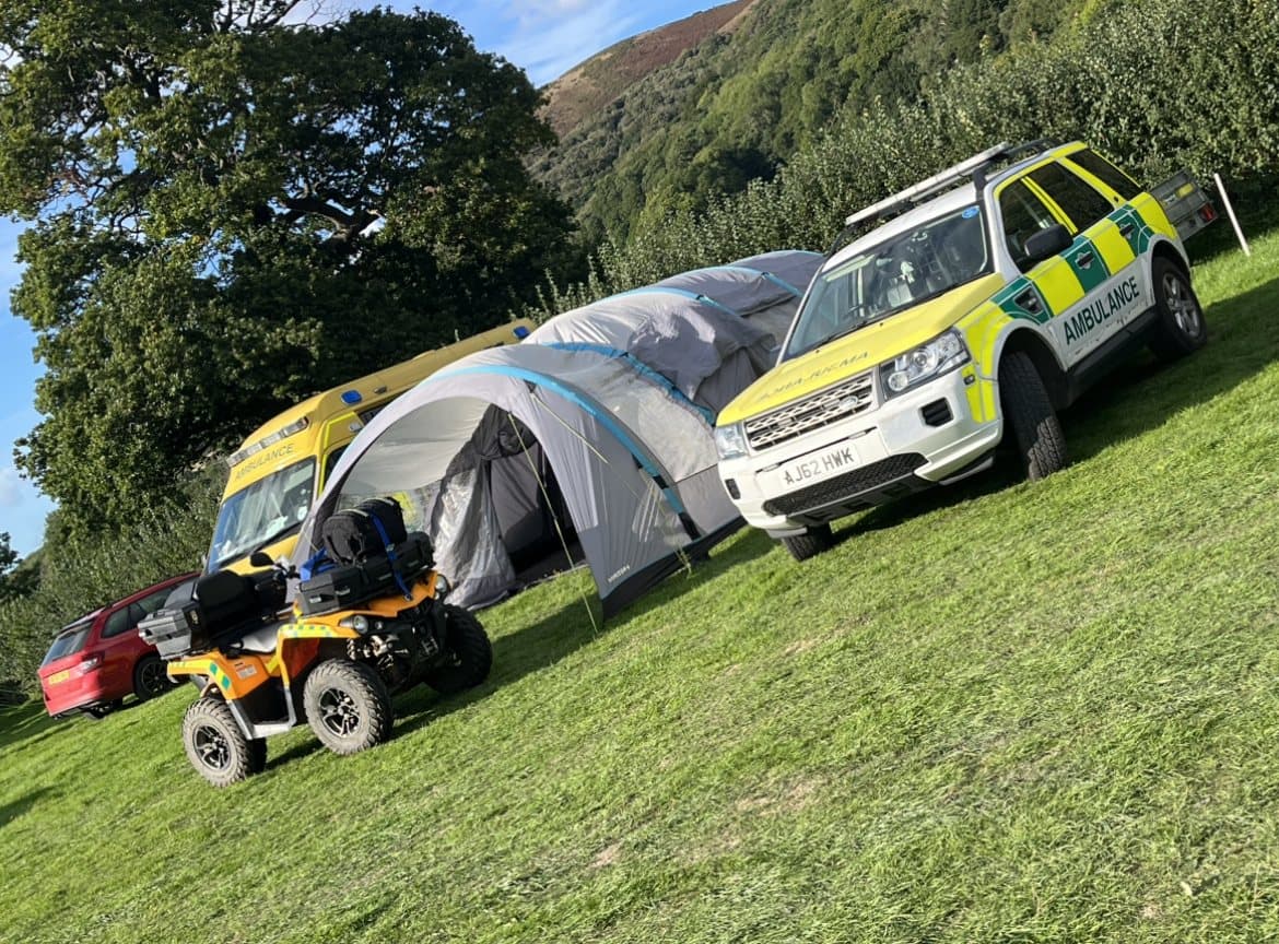 AAA.AMBULANCE3 vehicles, treatment tent and ambulance quad bike set up on a hillside event site